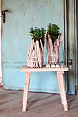 Original planters made from tied bundles of pale driftwood on wooden stool in front of vintage door