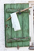 Tea towel on coat hanger hand-crafted from branch hung on peeling green window shutter
