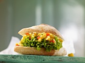 A baguette roll filled with scrambled egg, tomatoes and lettuce