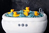 A cake decorated in white fondant to look like a bathtub with rubber ducks