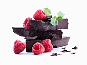 Several chunks of cooking chocolate with fresh raspberries