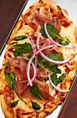 Pizza mit Prosciutto und roten Zwiebeln