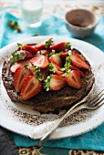 A small chocolate cake topped with fresh strawberries