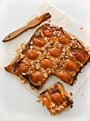 Apricot tart with sliced almonds, one slice cut