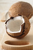 A whole coconut and one broken open, on a wooden board