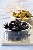 Black and green preserved olives in glass ramekins