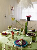Table set with a green tablecloth in a white wood paneled dining room