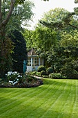 Frisch gemähter Rasen im großzügigen Garten mit Blick auf nostalgischen Gartenpavillon im Hintergrund in Sommerstimmung