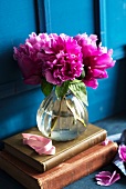 Pink peonies in a glass vase on antique books