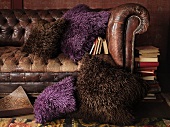 An old leather sofa with decorative cushions in brown and purple