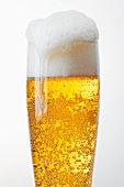 Ein Glas helles Bier mit überfliessendem Bierschaum