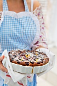 A woman serving cherry cake dusted with icing sugar