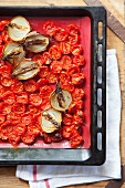 Roasted cherry tomatoes and onions in a baking tray