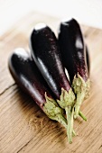 Several aubergines on a wooden board