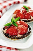 Individual strawberry tarts with mint leaves