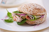 A sandwich filled with spinach, prosciutto, cucumber and onions