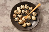 Quail's eggs in a bowl with a wooden spoon