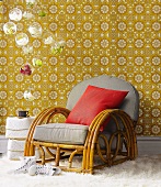 Art Deco rattan chair in front of vintage floral wallpaper and hanging glass balls with orchid flowers