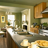 Küche im Landhausstil mit pastellgrünen Wänden, Holzmöbeln, offenem Kamin und Essplatz