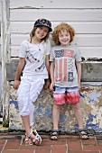 Two children leaning against the weathered stone foundation of an old home