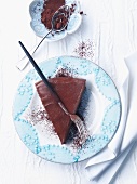 A slice of chocolate cake with cocoa powder