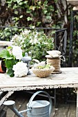 weiße Hortensien neben Schale mit selbstgefertigter Strickhülle und Garnrolle auf Vintage-Gartentisch