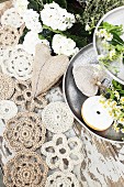 Doilies hand-crocheted from jute yarn and hessian heart next to doughnut and chamomile on metal cake stand