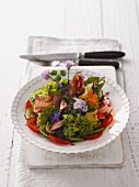 Colorful salad plate with edible flowers and bacon