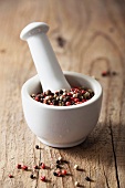 Colorful peppercorns in a mortar on a wooden background