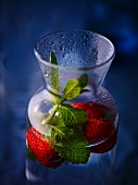 A carafe of water with strawberries and mint