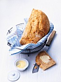 Yoghurt and sesame seed bread in a bread basket, with butter