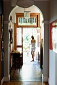 View of woman and child in hallway of traditional house seen through arch