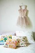 Scatter cushions with cheerful floral patterns on bed and tutu hanging on wall