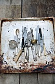 Antique cutlery on a rusty baking tray