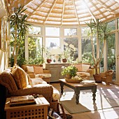 Light-flooded conservatory with wicker sofa set and traditional-style coffee table with turned wooden legs