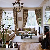Classic sofa set and metal-framed coffee table on pale rug in front of French windows with beige, striped curtains