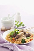 Lamb kebabs with peanut sauce on noodles