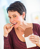 A woman nibbling on a piece of chocolate
