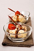 A layered ice cream dessert with strawberries and caramel sauce