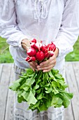A woman holding a bunch of radishes