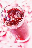 A forest berry smoothie in a glass on a red and white surface