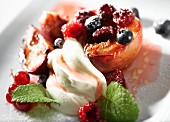 A baked peach with berries and cream