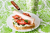 A slice of bread topped with cream cheese, strawberries, smoked chicken breast and cress