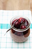 Chocolate mousse with stewed cherries in a small preserving jar