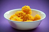 Sweet egg yolk nests in a white bowl on a purple surface