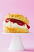 Scone with clotted cream and strawberry jam on a mini cake stand