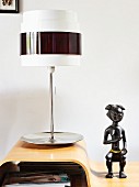 Retro table lamp with metal base next to ethnic stone figurine on moulded wood table