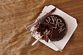 Schokoladenkuchen auf einem Kuchenteller, teilweise mit Gabeln gegessen und ein Messer