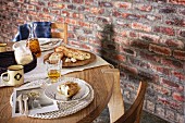 Baked goods on round oak table next to rustic brick wall