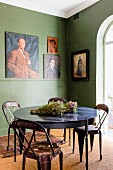 Retro Metallstühle um runden Tisch in grün getönter Zimmerecke und Gemälde an Wand
